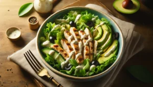 A grilled chicken and avocado salad with black olives and creamy dressing.