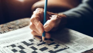 An image of an elderly hand holding a pencil, working on a crossword puzzle.