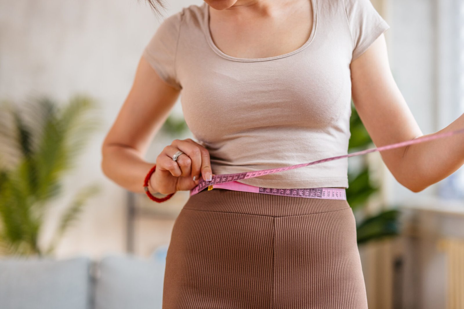 A woman uses a measuring tape to measure her weight loss progress on a flax seed diet.
