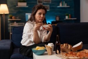 A woman sitting on the couch, having a takeout food binge.