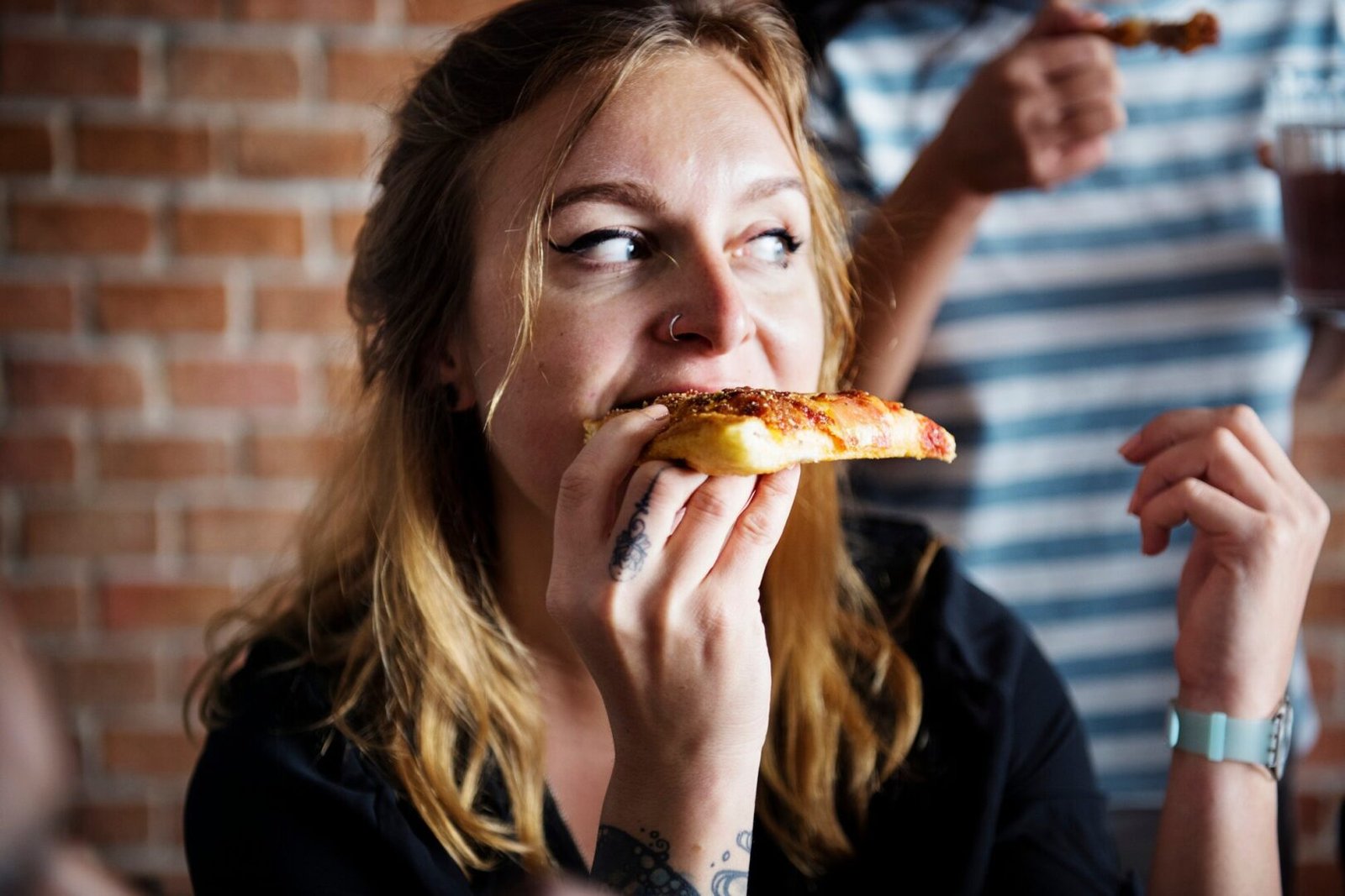 A woman eating pizza and looking unhappy