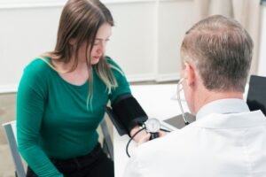 A doctor uses a cuff to measure a female patient's blood pressure