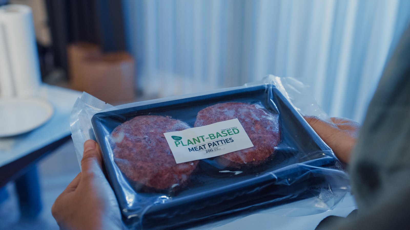 A person holds a package of vegan, plant-based burger patties