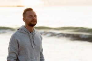 A man relaxes outdoors with headphones, feeling peaceful.