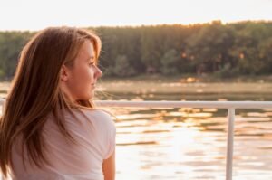 A young woman looks peacefully out at the water.