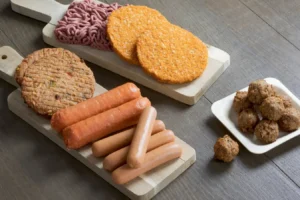 An image of highly-processed, plant-based, vegan meat substitutes, including hotdogs, patties, meatballs and sausages.