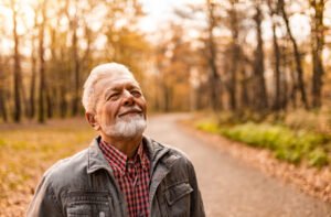 An older man enjoys a pain-free walk on an outdoor trail.